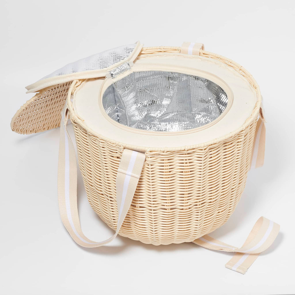 Sunnylife Round Plastic Rattan Insulated Picnic Cooler Basket in Le Weekend with natural and white webbed straps, side view with cover unzipped to show silver insulated lining inside.