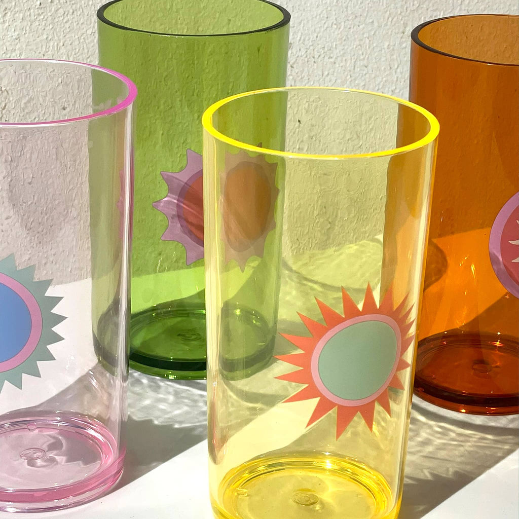 Sunnylife Rio Sun Poolside Tall Acrylic Tumbers, set of 4 with different sun graphics, photographed in sunlight with reflections.