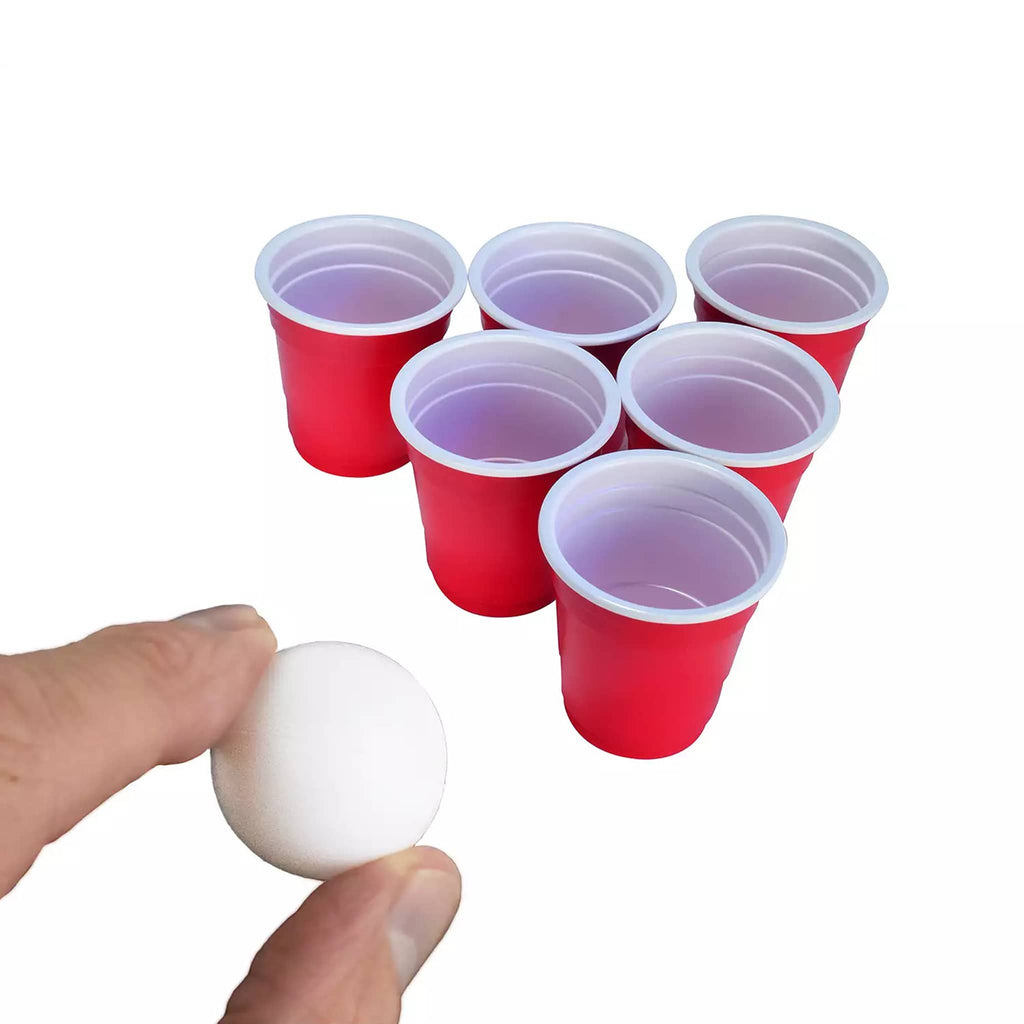 Mini red plastic cups with mini white ping pong ball on a white background.