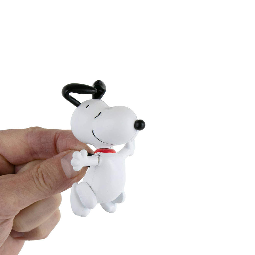 World's Smallest Dancing Snoopy Peanuts toy held by finger against a white background.