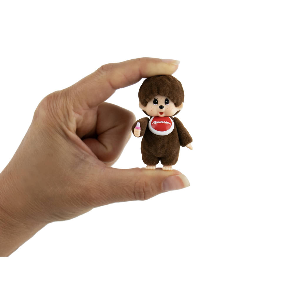 World's Smallest Monchhihi figurine held by a hand, on a white background.
