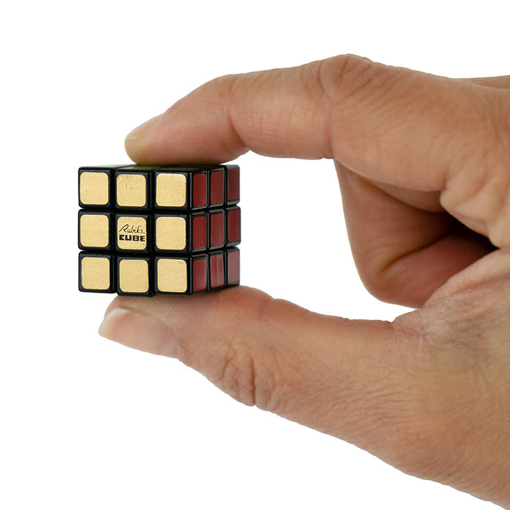 Super Impulse World's Smallest Rubik's Cube 50th anniversary collectors edition in between fingers for scale.