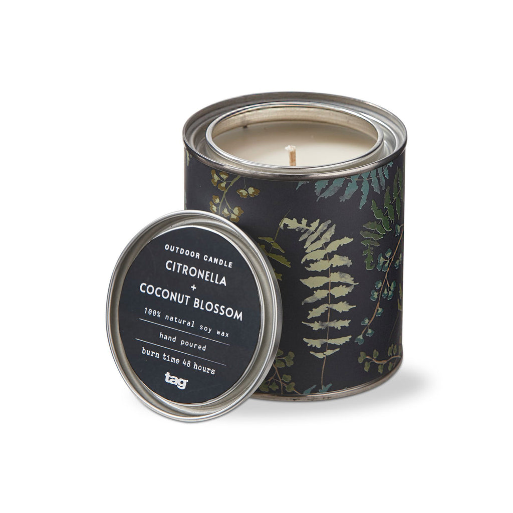 Tag Ltd Citronella + Coconut Blossom scented soy wax candle in metal tin with lid and leafy plant illustrations in shades of green on a black background. 