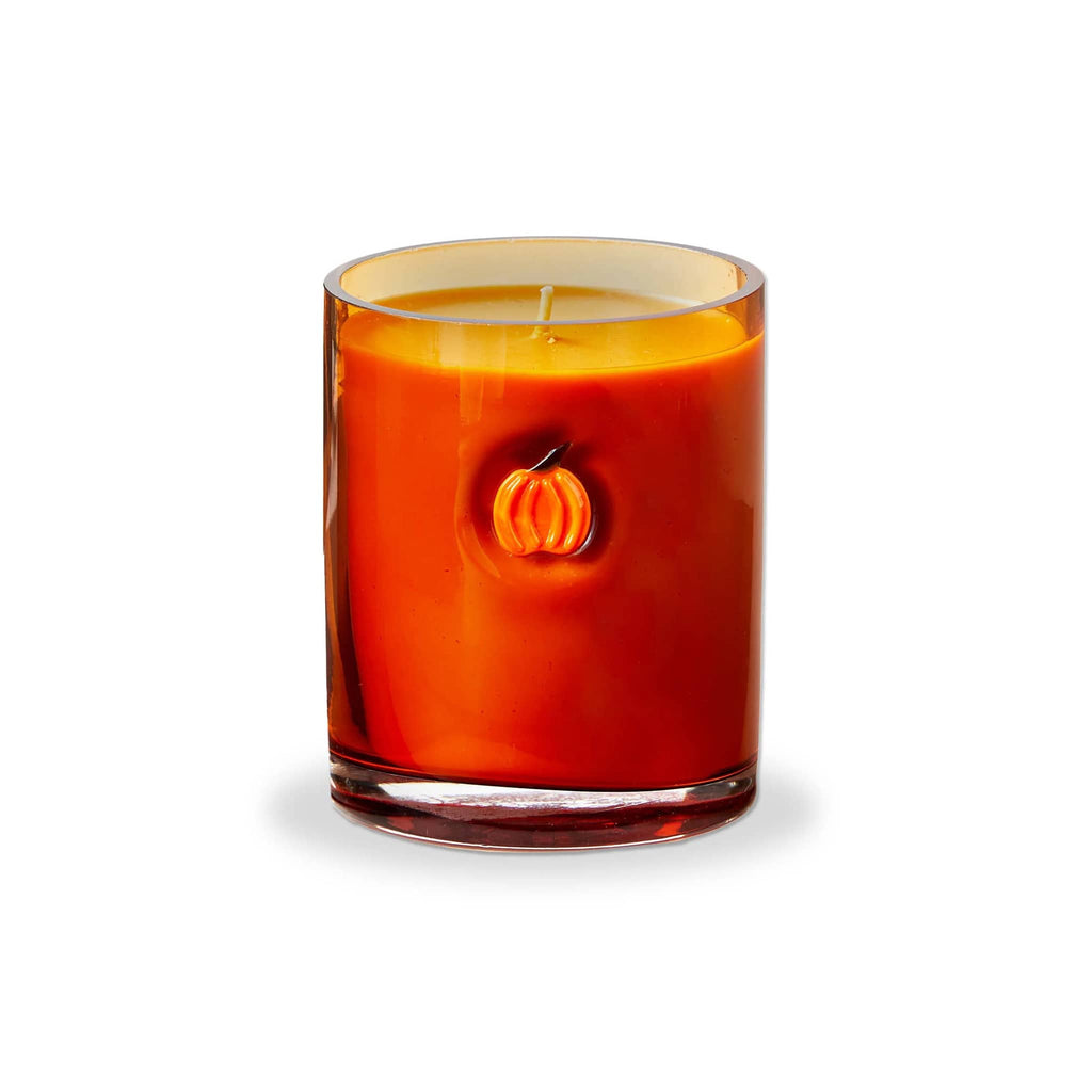 Candle in an amber glass container with a pumpkin design on a white background.