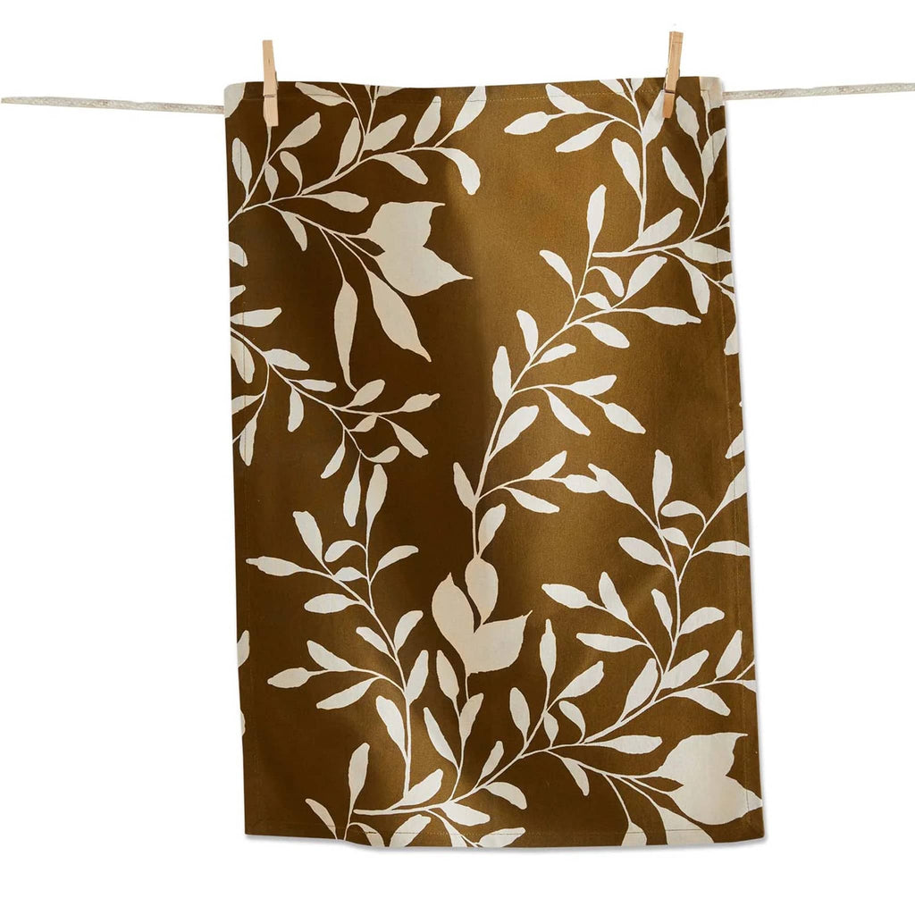 Brown towel with white leaf pattern hanging on a line with clothespins on a white background.