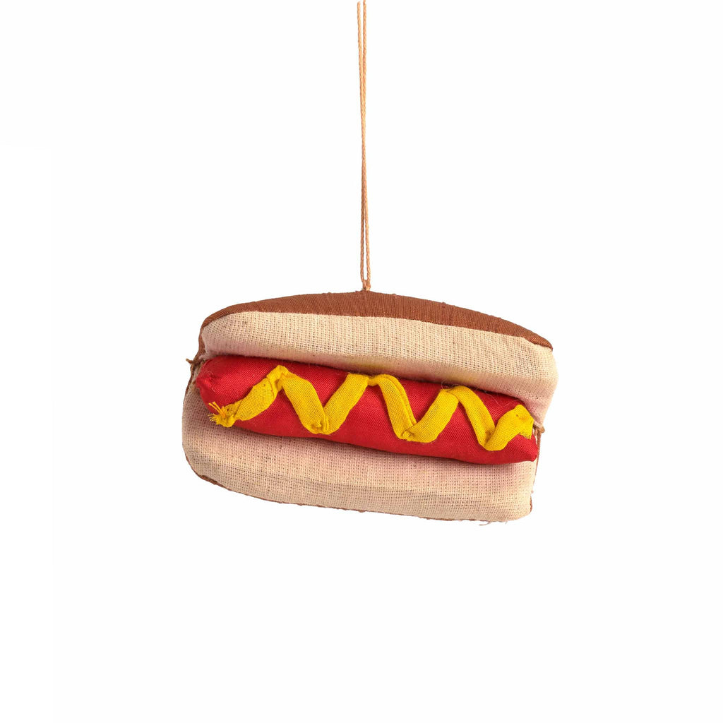 Hot dog-shaped fabric ornament with bun and mustard on a white background.
