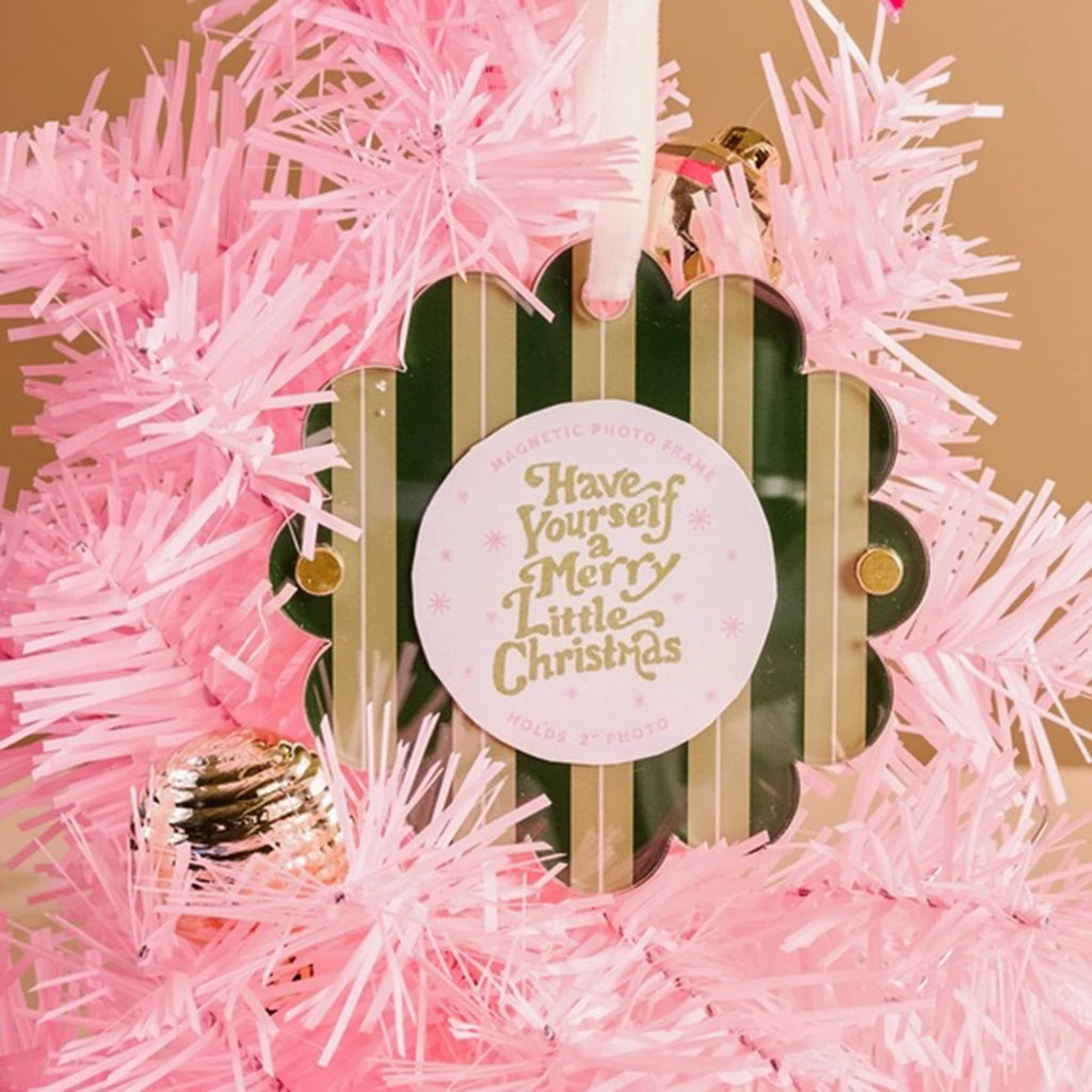 Green striped acrylic round magnetic photo frame with scalloped edge and a white ribbon loop on a pink holiday tree.