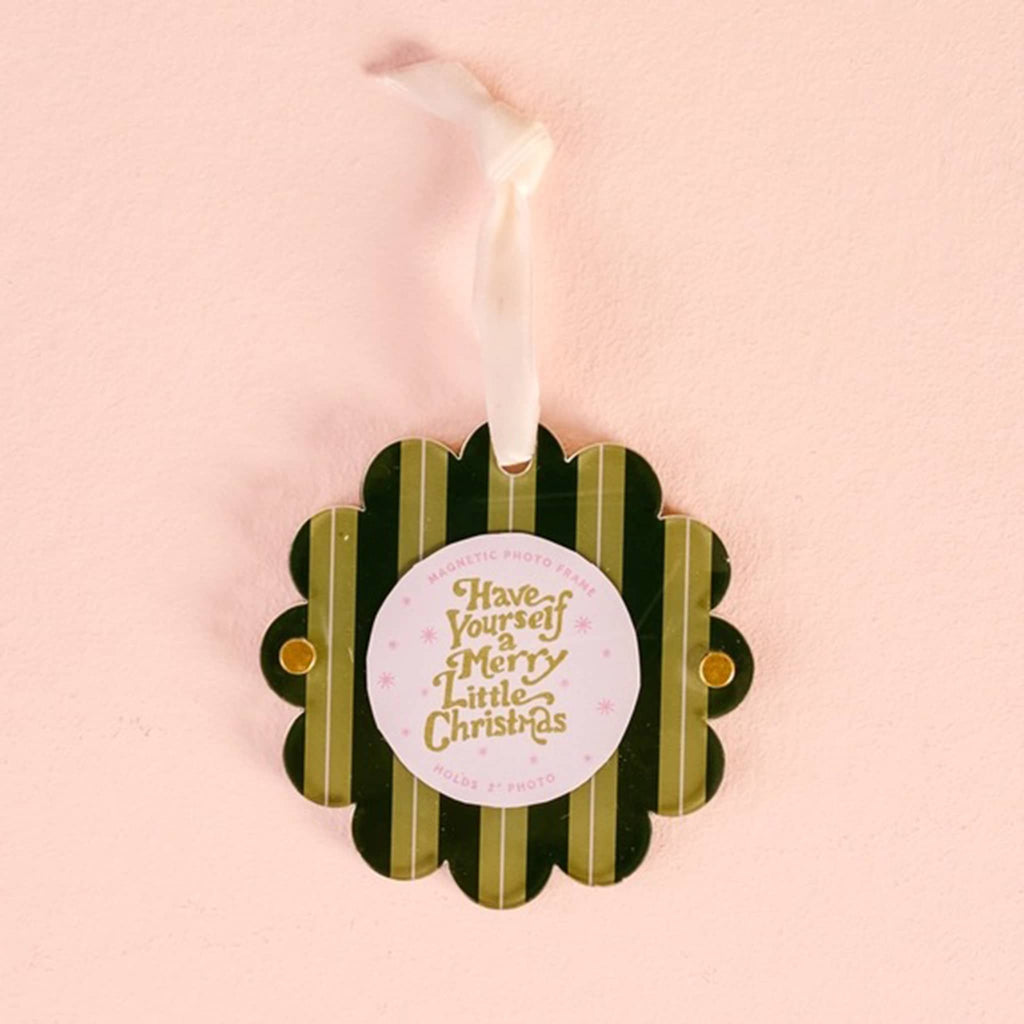 Green striped acrylic round magnetic photo frame with scalloped edge and a white ribbon loop on a pink background.