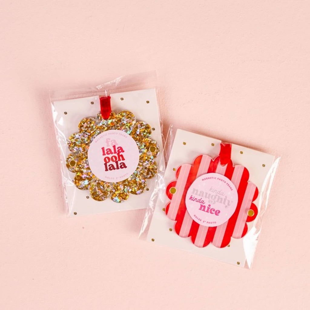 Two round magnetic photo frames with scalloped edge and a red ribbon in cellophane packaging, on a pink background.