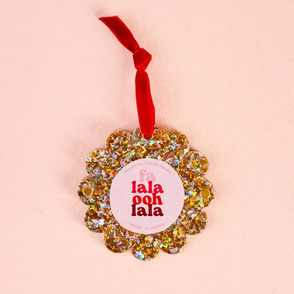 Gold glitter round acrylic magnetic photo frame with scalloped edge and a red ribbon loop on a pink background.
