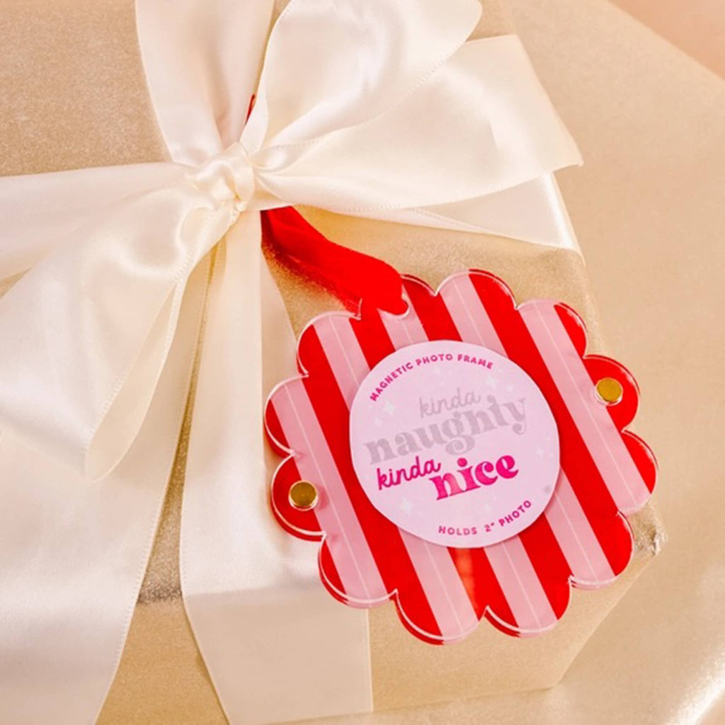 Red and pink striped photo frame with 'kinda naughty kinda nice' text on a gift box with a bow.