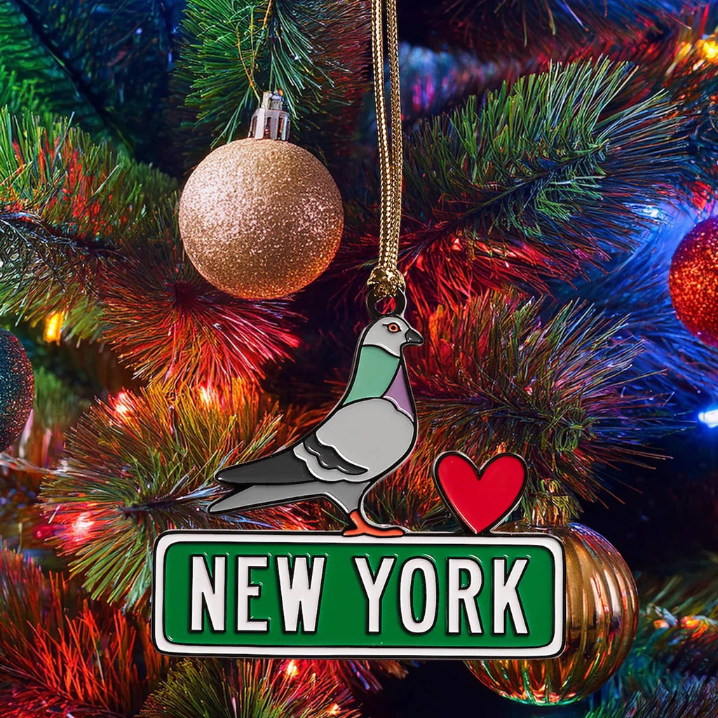 Pigeon enamel ornament with 'New York' street sign and a heart hanging on a Christmas tree.