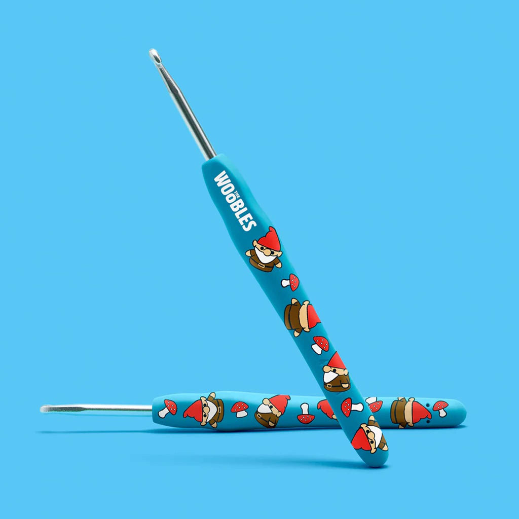 2 blue crochet hooks with gnome designs on a blue background.