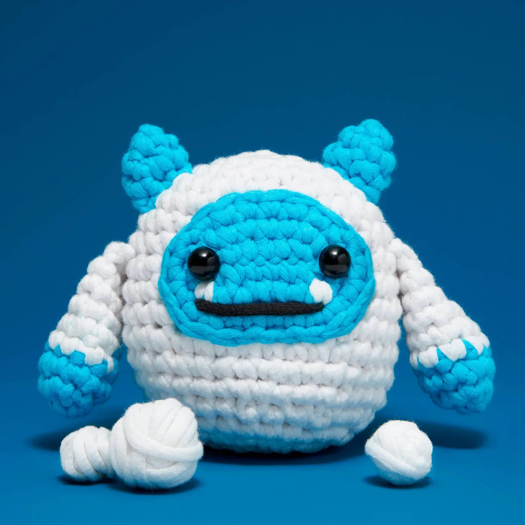 Crocheted blue and white yeti on a blue background.