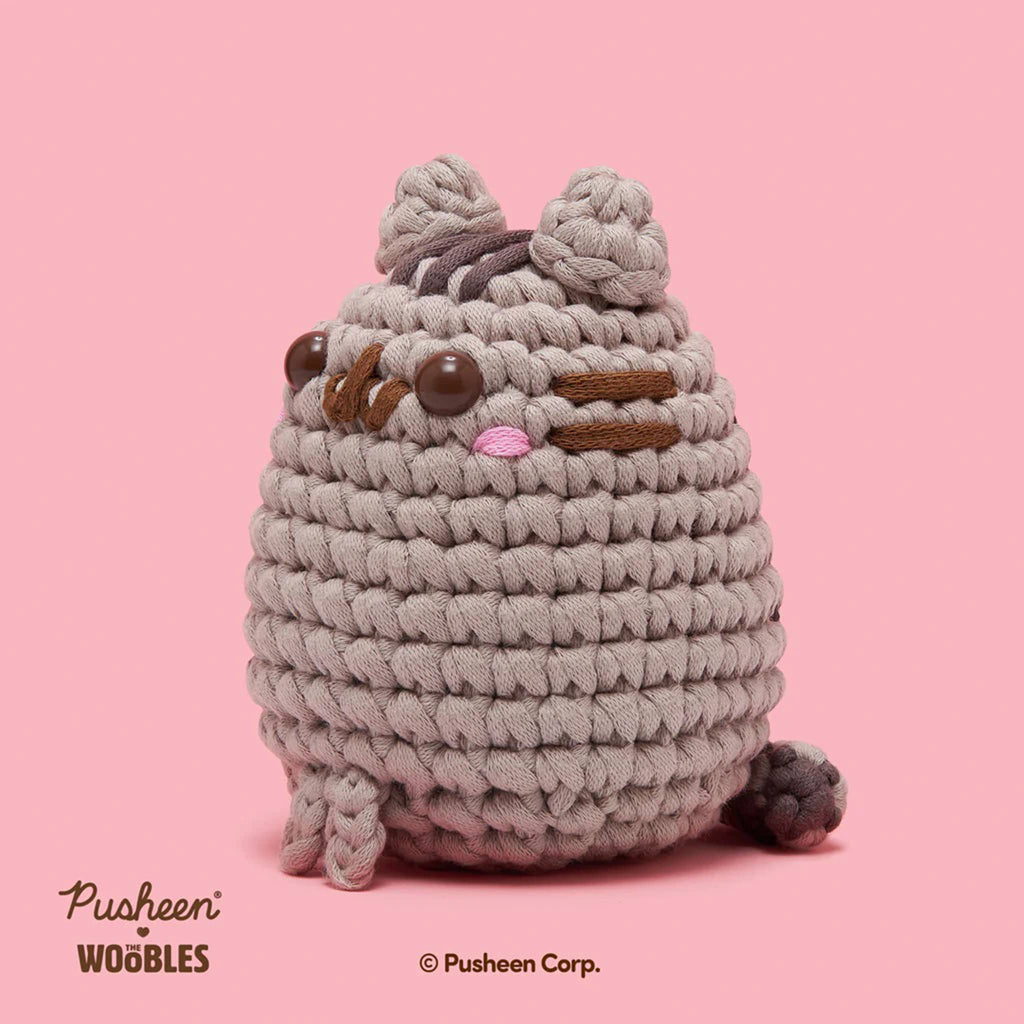 Finished The Woobles Pusheen beginner crochet kit project, side view, on a pink background.