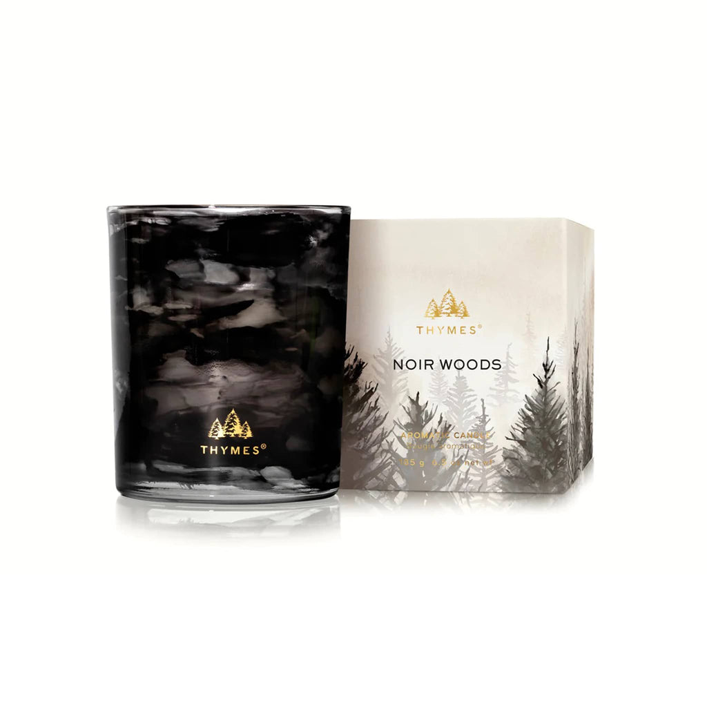 Thymes Noir Woods candle in black marbled glass container and gold logo, with gift box, on a white background.