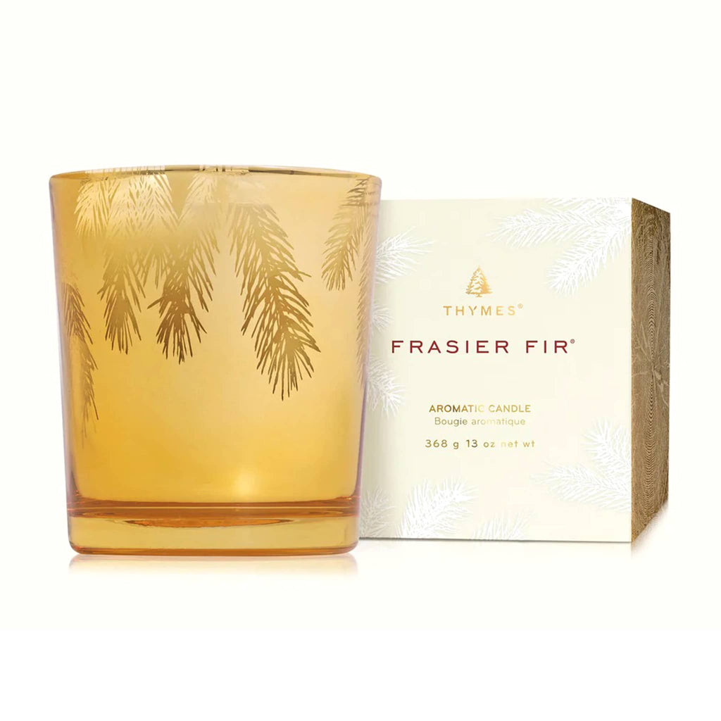 Thymes Frasier Fir candle in gold with pine needled design and packaging on a white background.