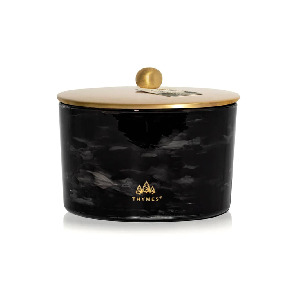 Thymes Noir Woods candle in black marbled glass container with gold lid and logo on a white background.