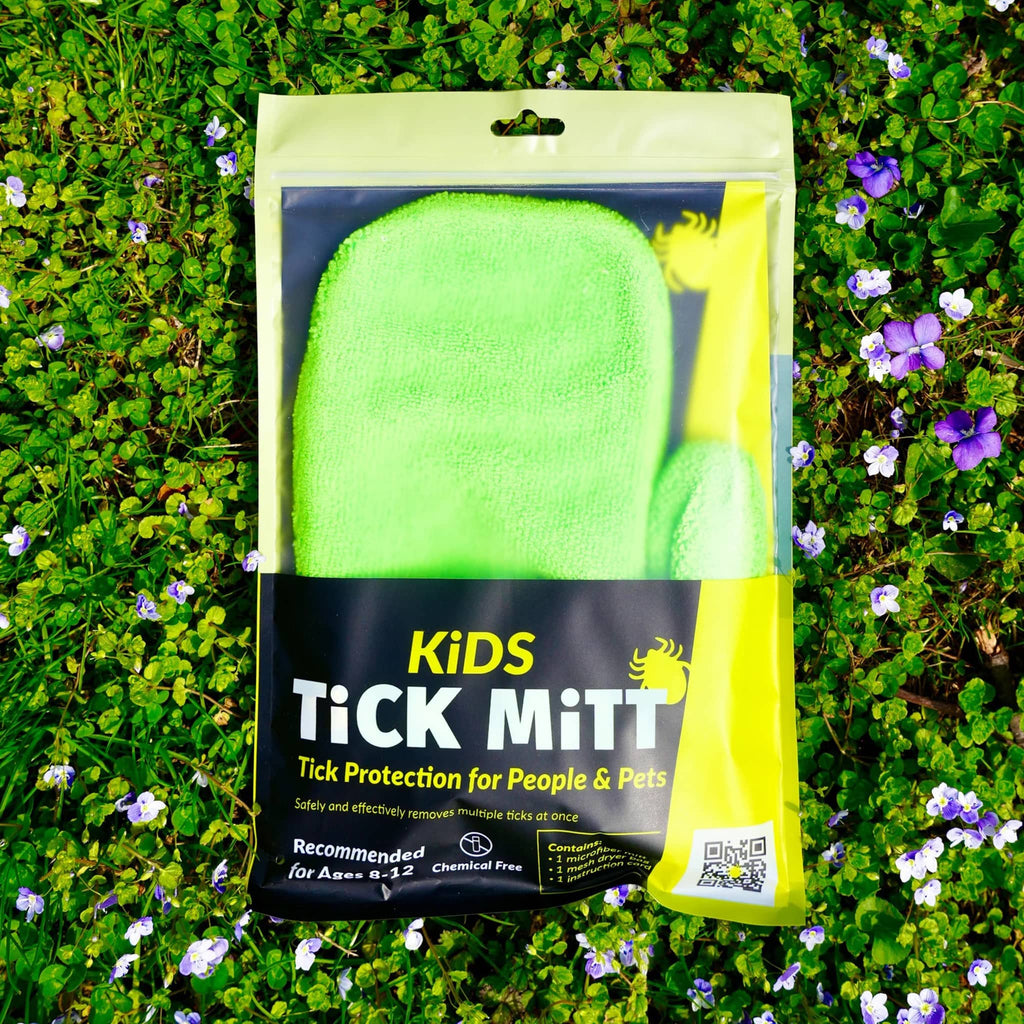 Kids Tick Mitt in green, in pouch packaging on grass.