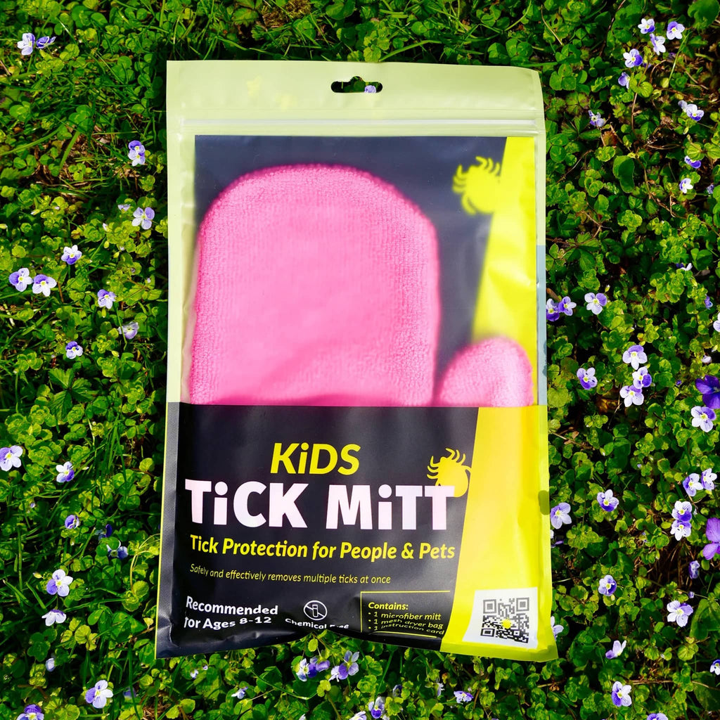 Kids Tick Mitt in pink, in pouch packaging on grass.