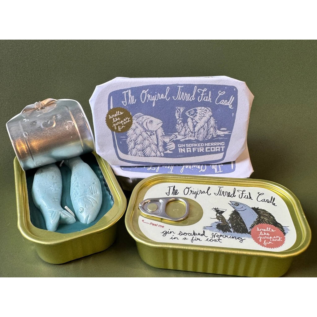 The Original Tinned Fish Candle Juniper and Fir scented holiday soy wax candle in sardine tin packaging, open showing blue shimmery wax fish inside, closed and closed with paper wrapping.