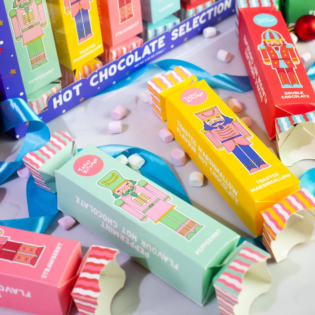 Colorful holiday crackers with nutcracker designs, with marshmallows and ribbon, on a white background.