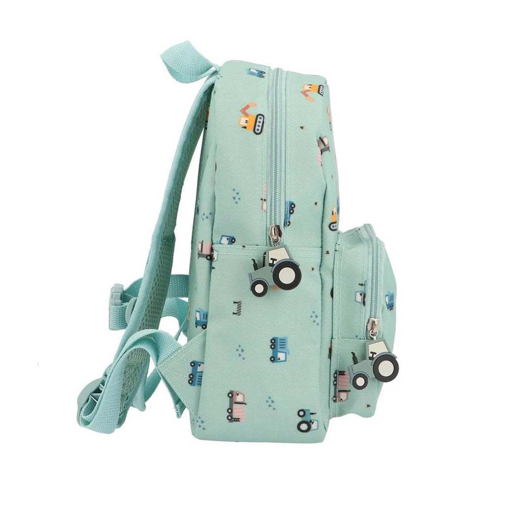Light blue backpack with small truck illustrations and tractor charm zipper pulls, side view on a white background.