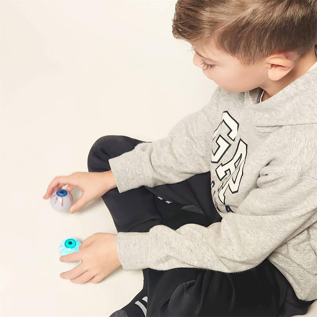 Child playing with floating eyeball toys on a light background.