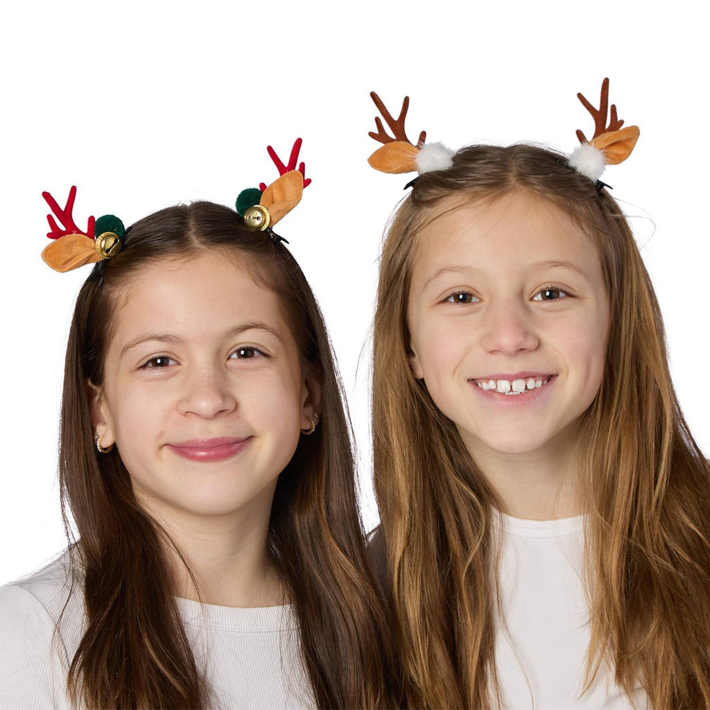 Two children wearing reindeer antler hair clips on a white background.