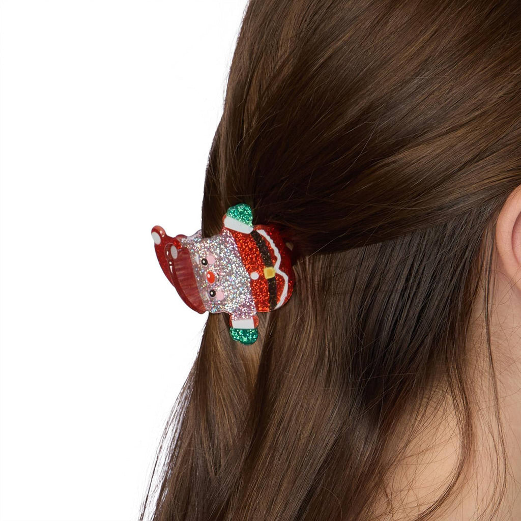 Decorative hair claw clip with a Santa Claus design on a person's ponytail against a white background.