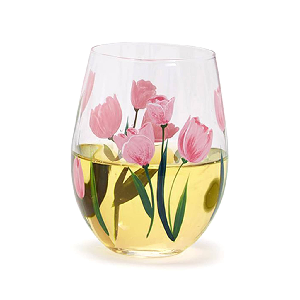 Two's Company clear stemless wine glass with pink tulips and green leaves, glass is filled halfway with white wine.