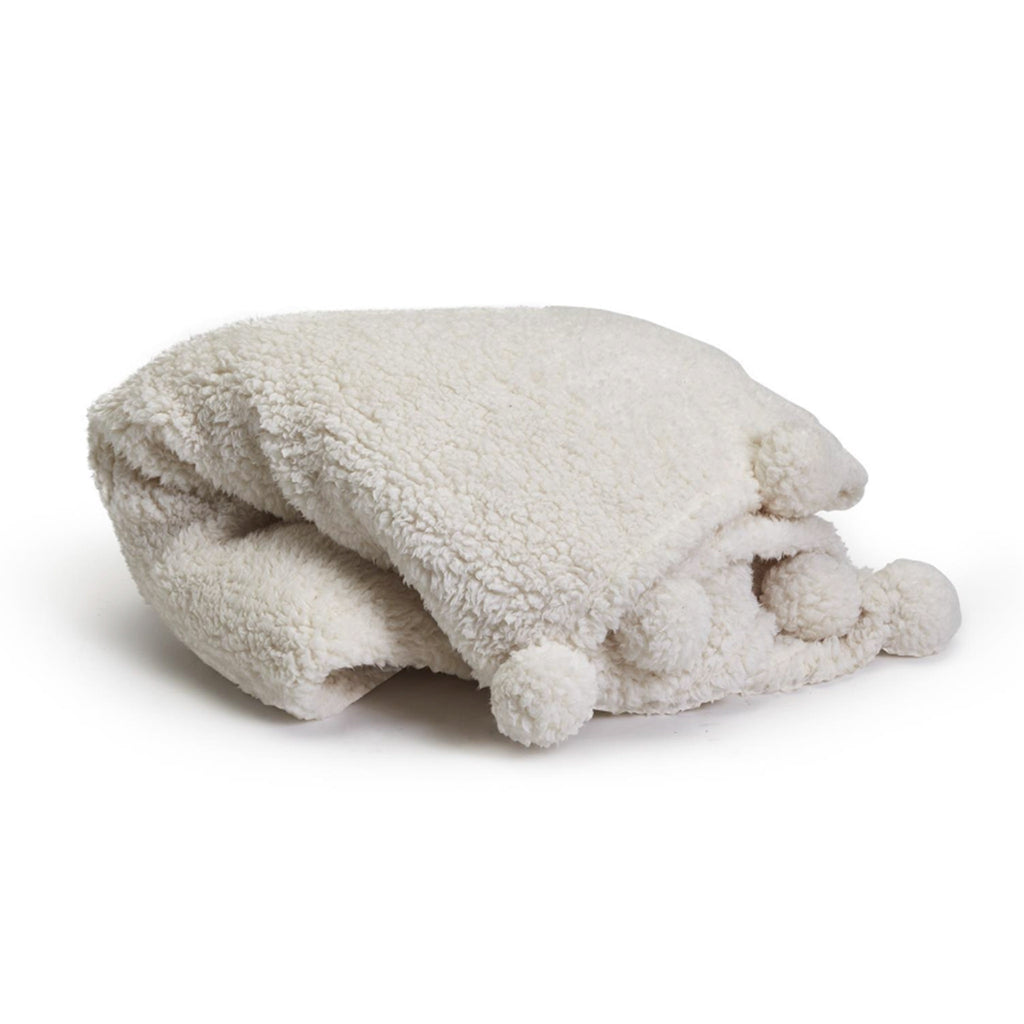Two's Company soft plush white faux sherpa throw blanket with pompoms, folded.