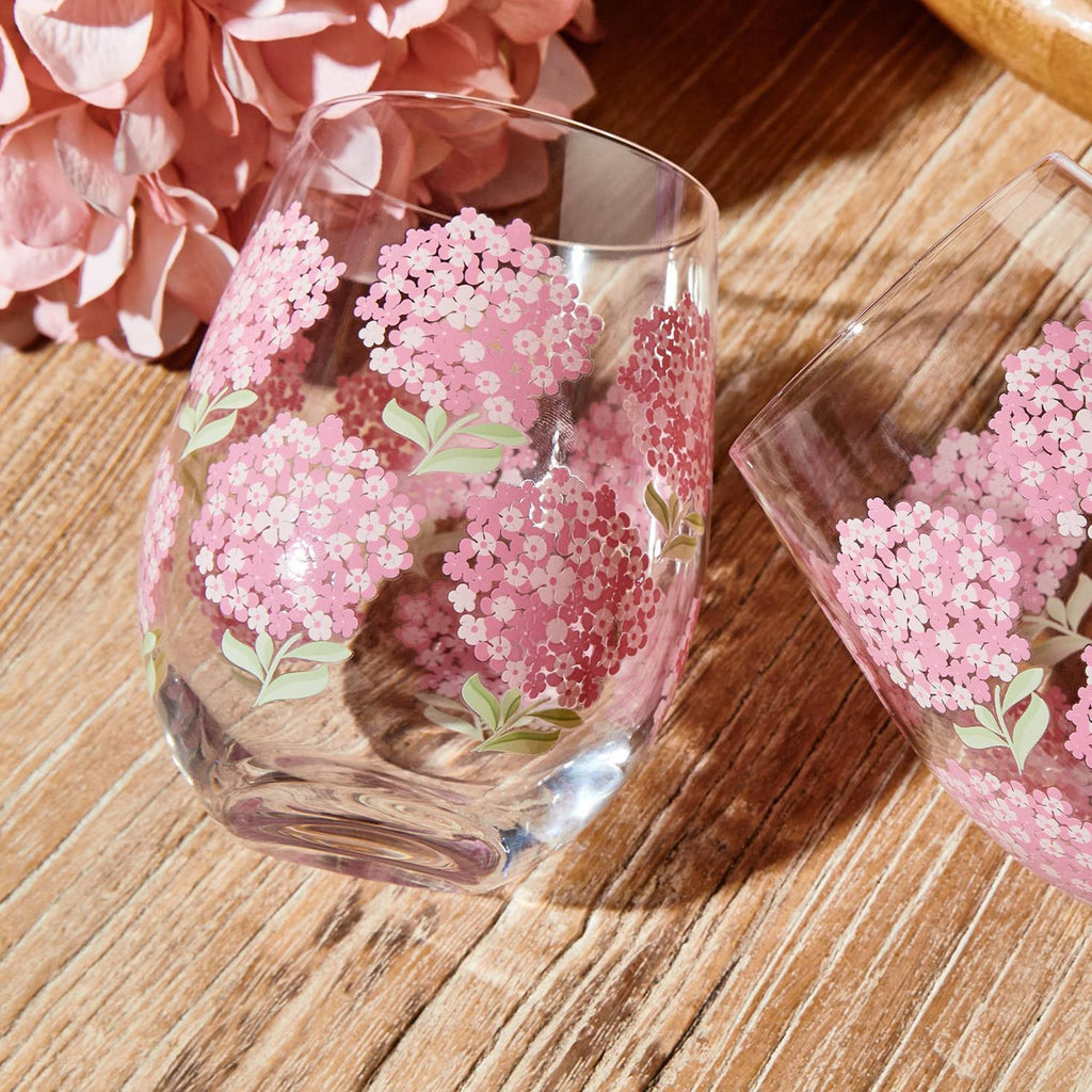 Two's Company Pink Hydrangea stemless wine glass, empty, on wood background.