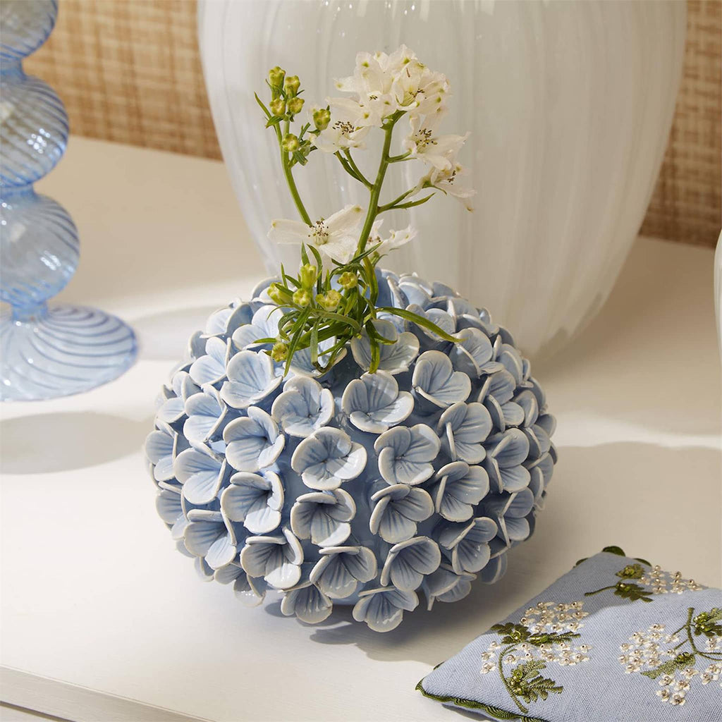 Two's Company Blue Hydrangea Porcelain Flower Bud Vase and Taper Holder, front view with white flower, in room setting.