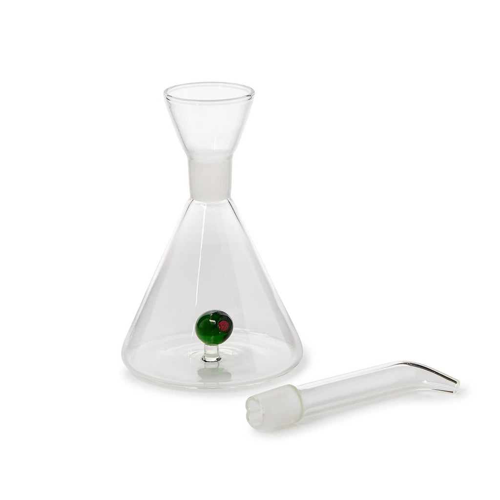 Clear glass oil dispensing carafe with a glass green olive inside, pour spout removed, on a white background.