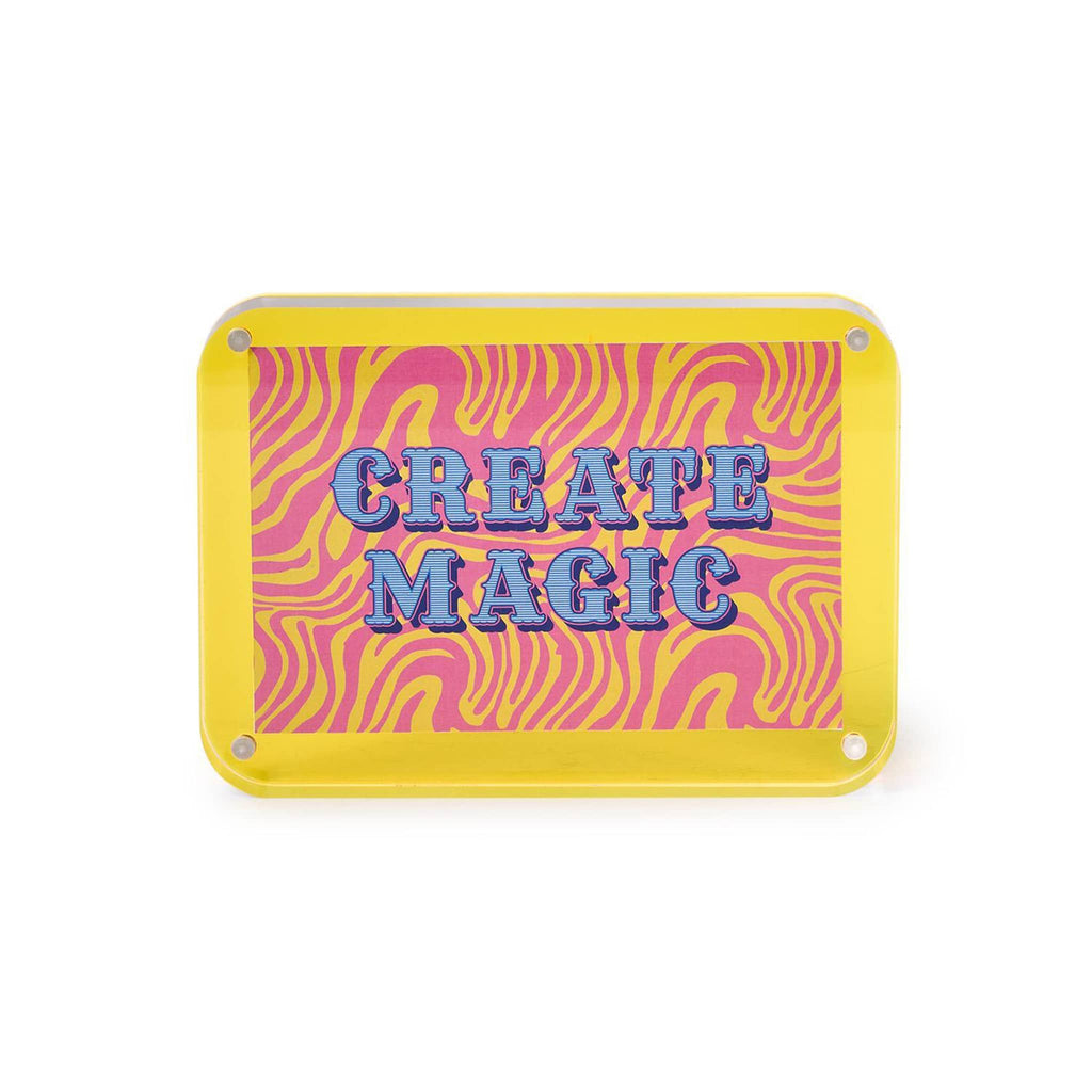 Yellow acrylic frame with insert that says 'Create Magic' on a pink and yellow zebra background, on a white background.