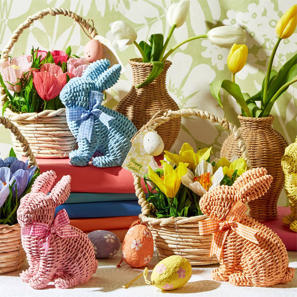 Two's Company resin sitting bunny with basket weave design and matching gingham bow in pink, blue and orange with baskets of spring flowers and paper mache eggs.