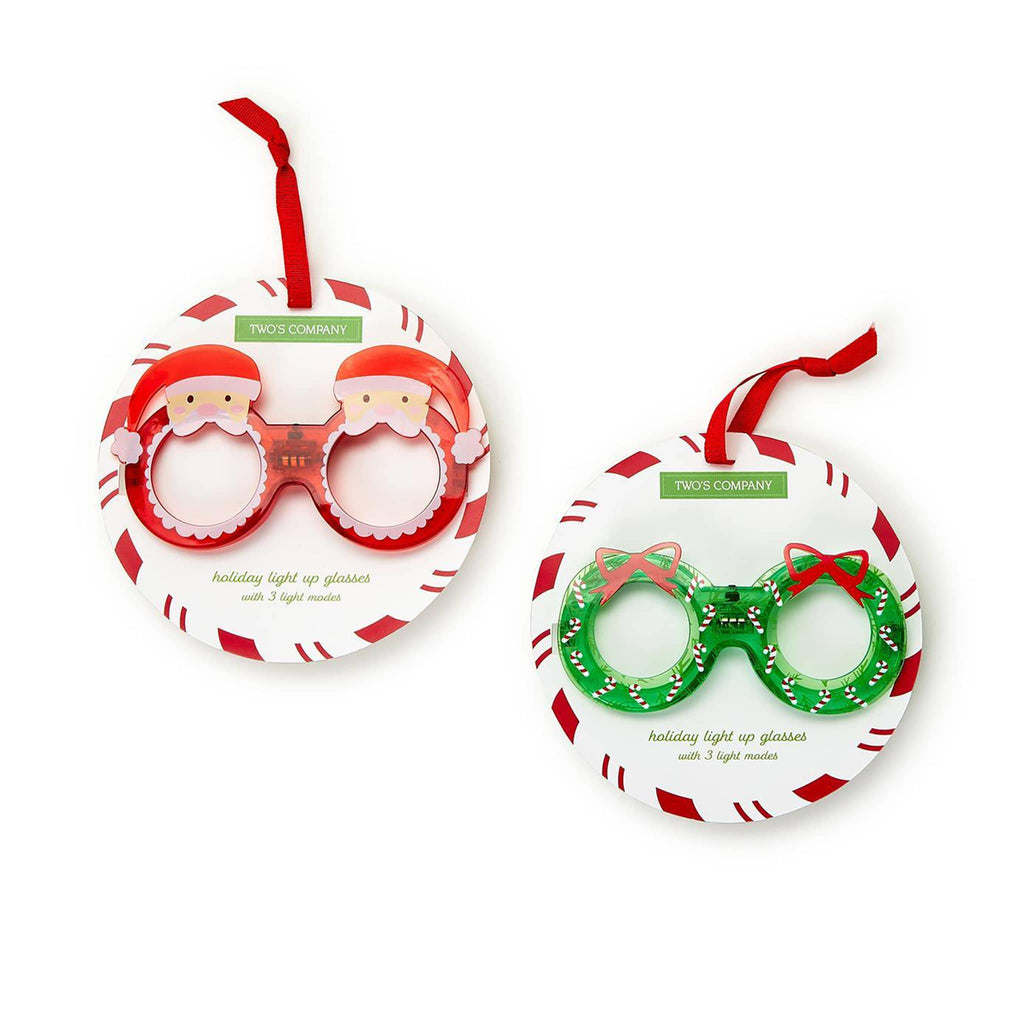 Two's Company Holiday Light Up Glasses in red santa and green wreath, on red and white candy card packaging.