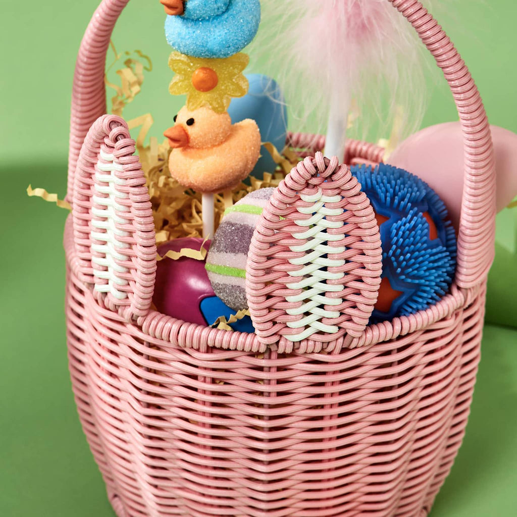 Two's Company Pink Faux Wicker Easter Basket with bunny ears, handle and pom pom tail, detail with fun toys and candy inside.