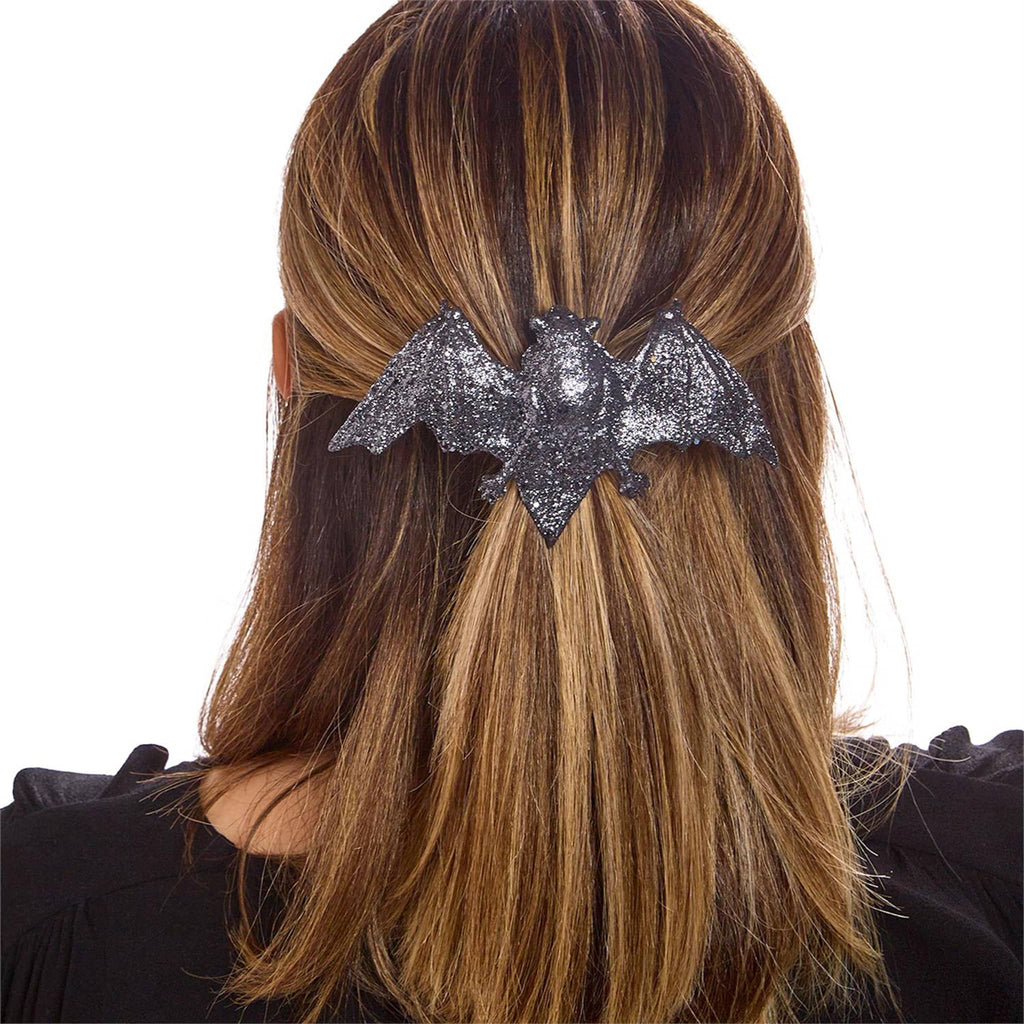 Person wearing a glittery bat-shaped hair clip on a white background.