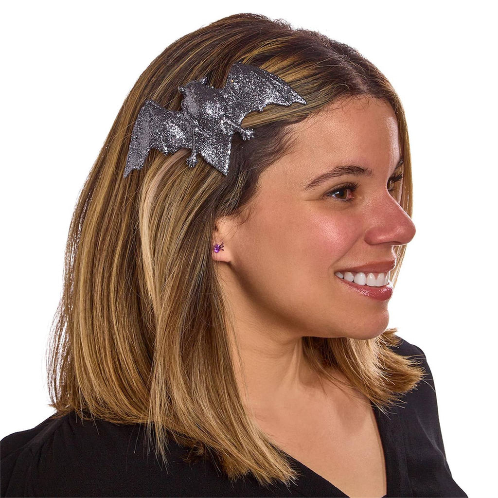 Woman wearing a silver bat-shaped hair clip on a white background.
