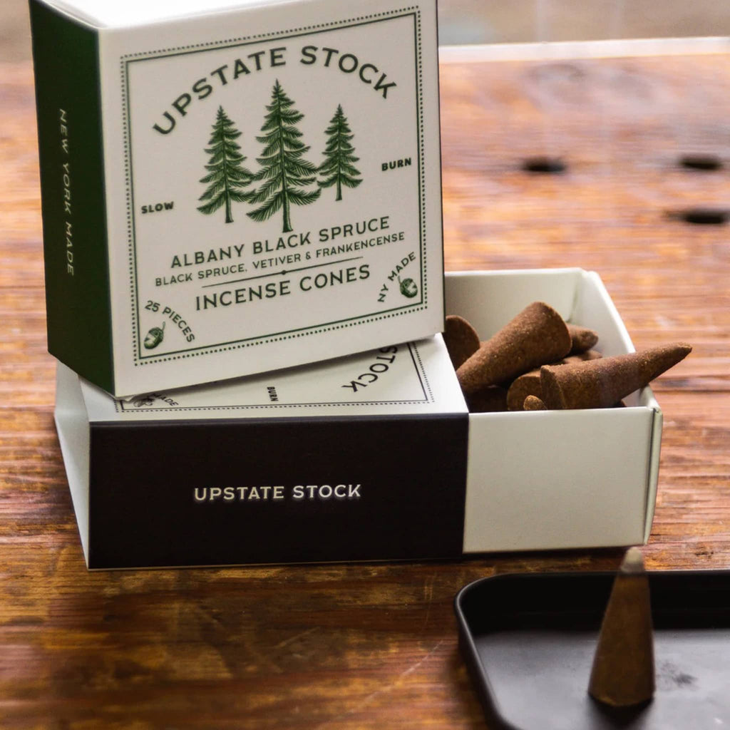 Upstate Stock Albany Black Spruce incense cones packaging on a wooden surface.