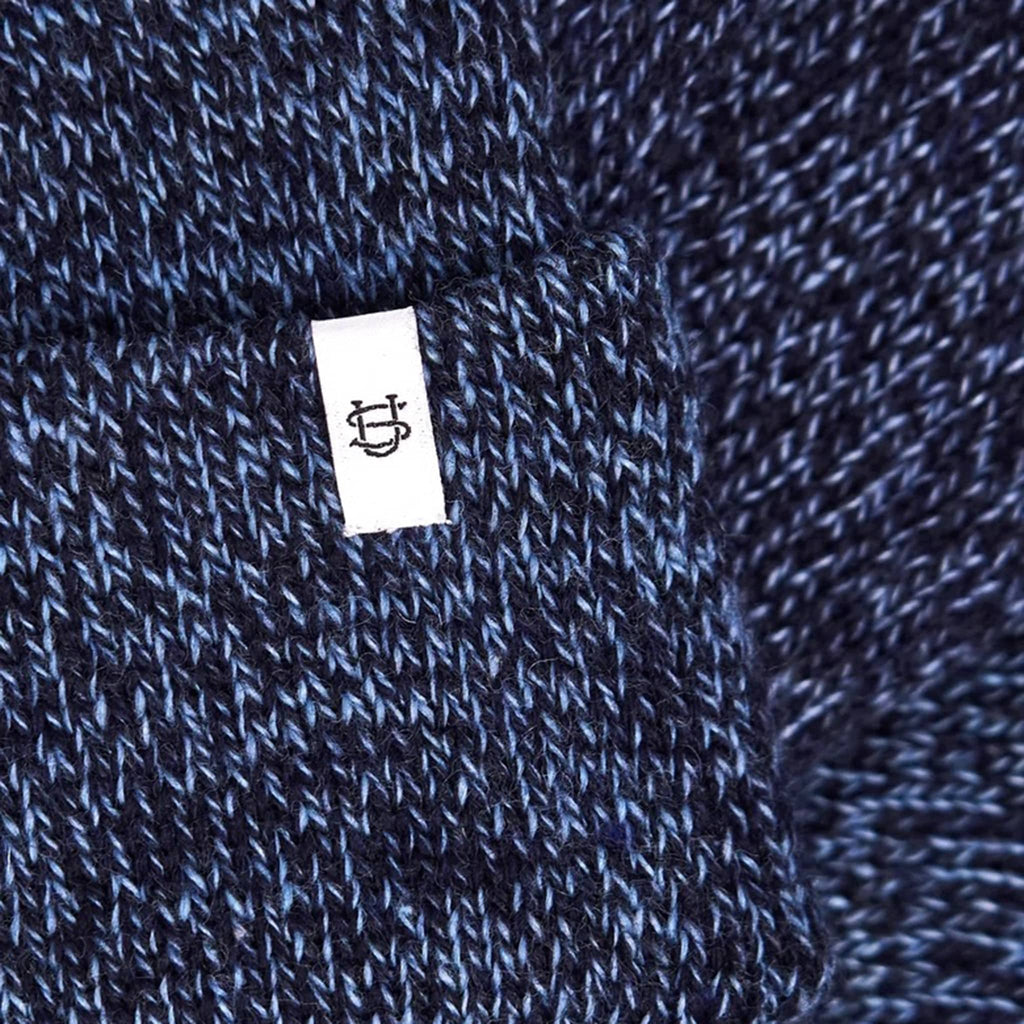 Close-up of blue and black knit fabric with a white label featuring a logo.