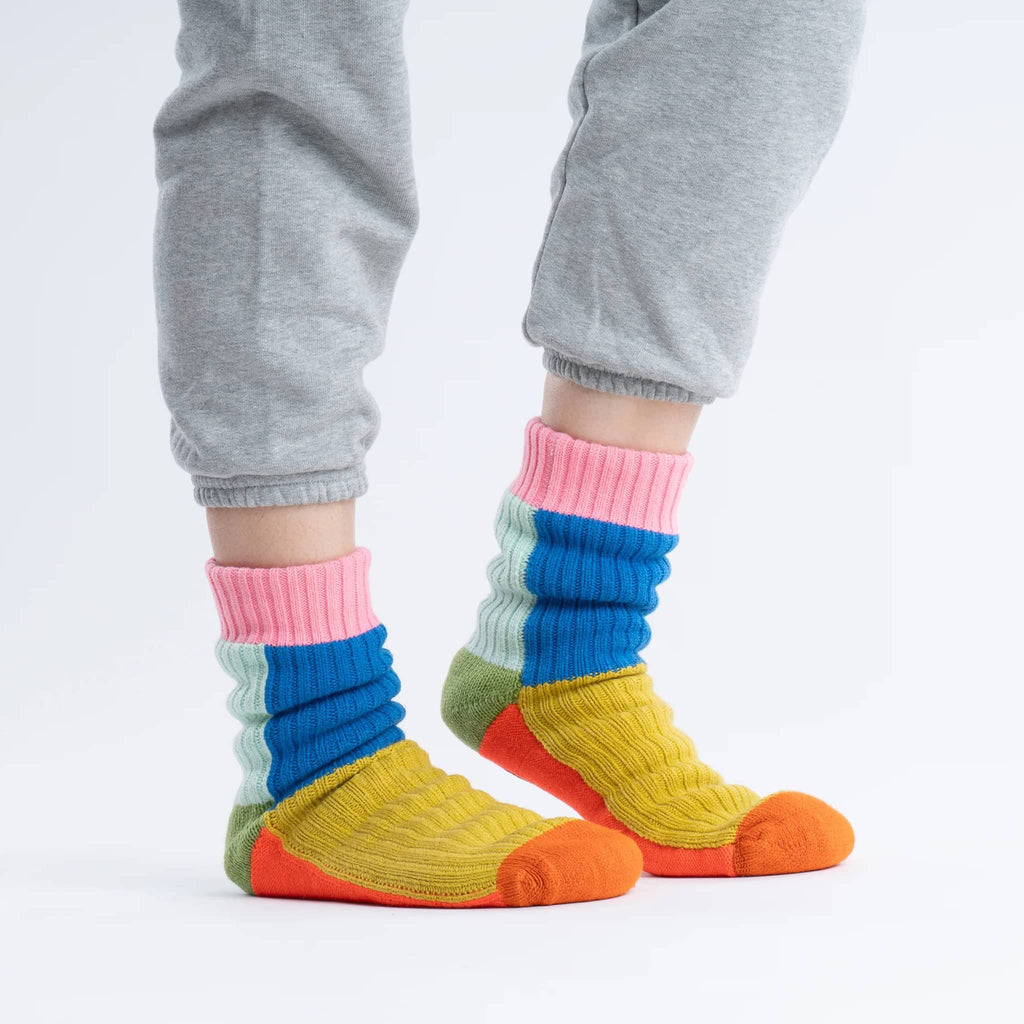Verloop Kaleidoscope color-blocked house slipper socks on model with gray sweatpants, on white background.