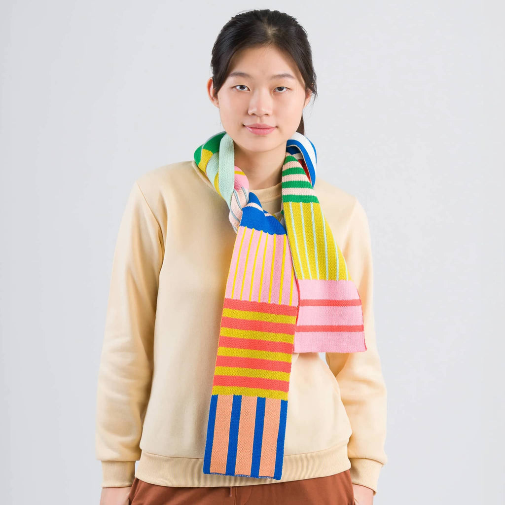 Verloop Patchwork Stripe Skinny Knit Scarf in rainbow colors on a model.