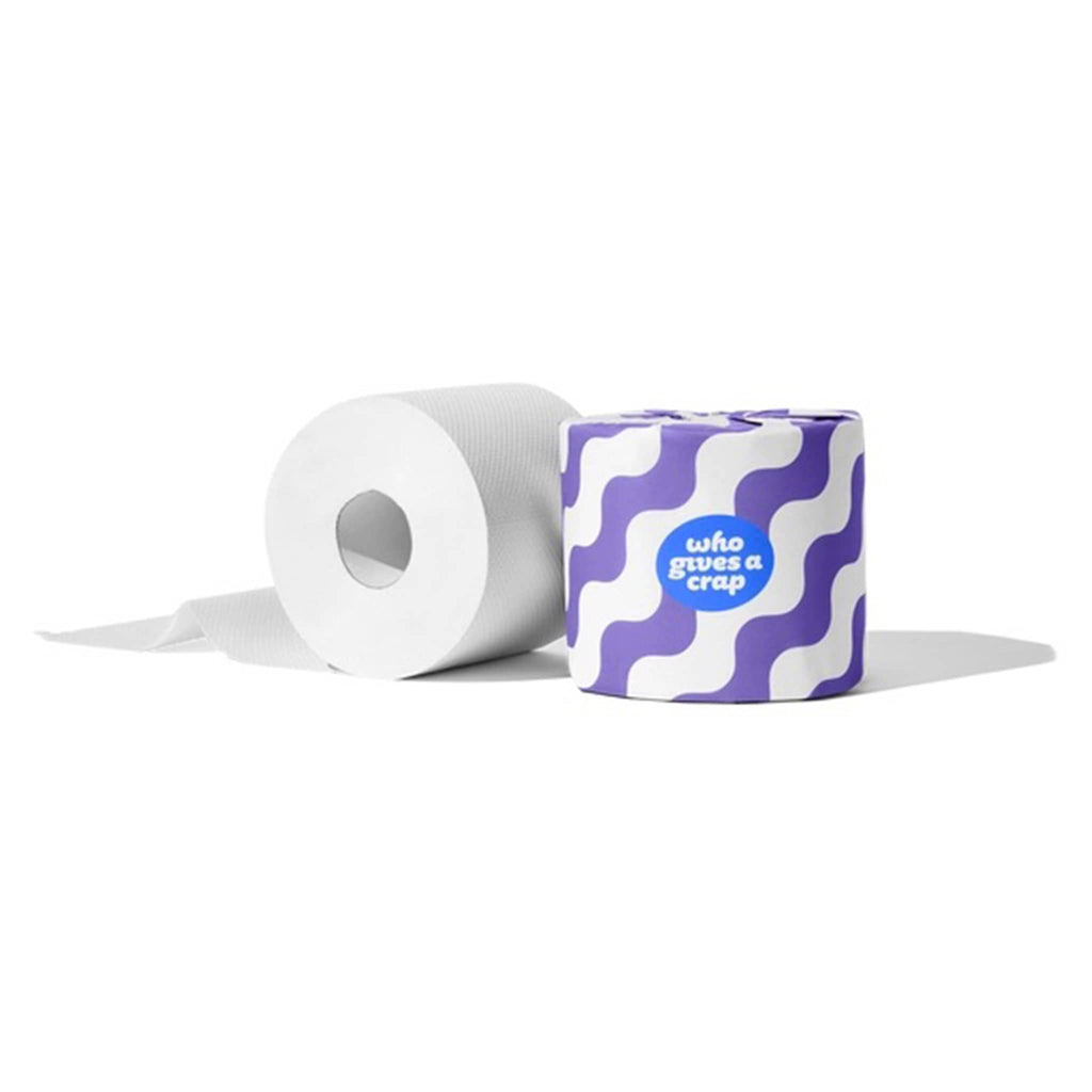 Who Gives a Crap 100% recycled toilet paper roll unwrapped beside purple and white wavy line wrapped roll.