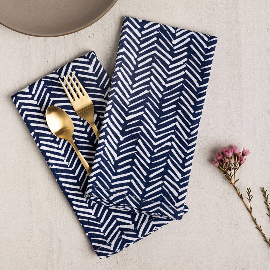 Wolf & Irving organic cotton napkins with a navy blue and white "tracks" pattern with a gold fork and spoon.