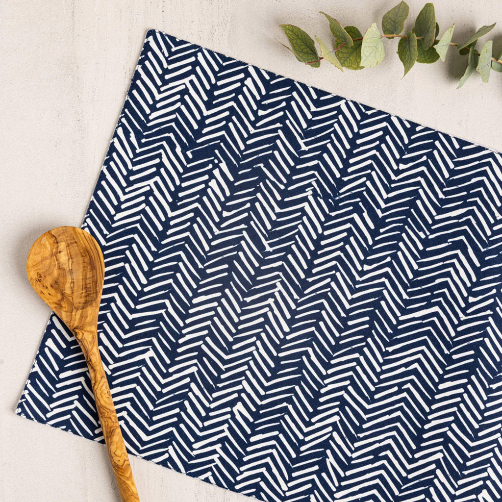Wolf & Irving organic cotton placemat with a navy blue and white "tracks" pattern with a wooden spoon.
