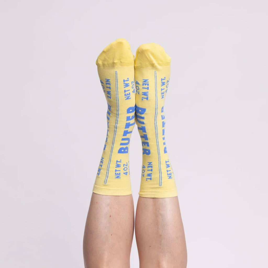 Yellow Owl Workshop small soft yellow crew socks that look like a stick of butter, on feet.