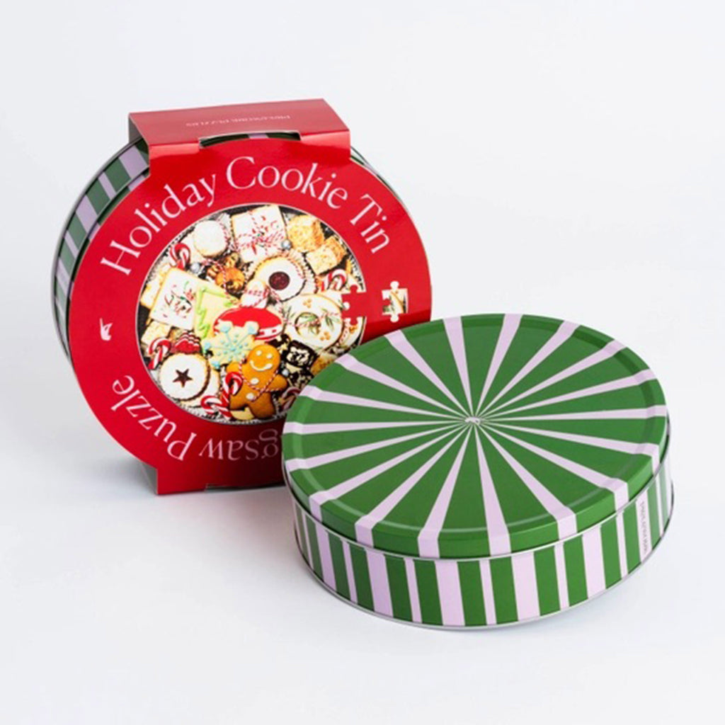 Piecework Puzzles 750 Piece Holiday Cookie Tin Round jigsaw puzzle in green and pink striped metal tin packaging and red sleeve with puzzle image.